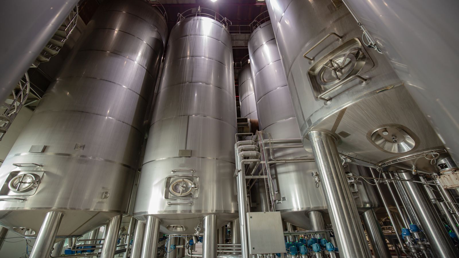 Insulated water buffer tank connected to piping in a greenhouse utility area