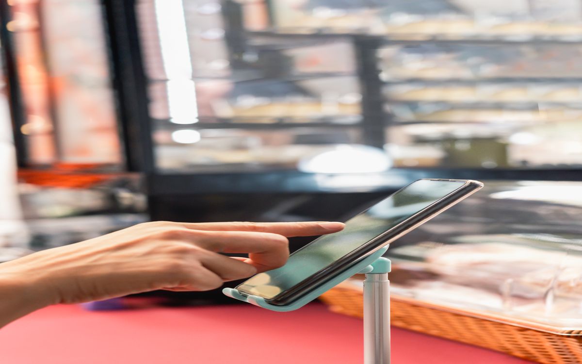Tablet displaying a Bitcoin payment QR code on a market counter beside packaged goods