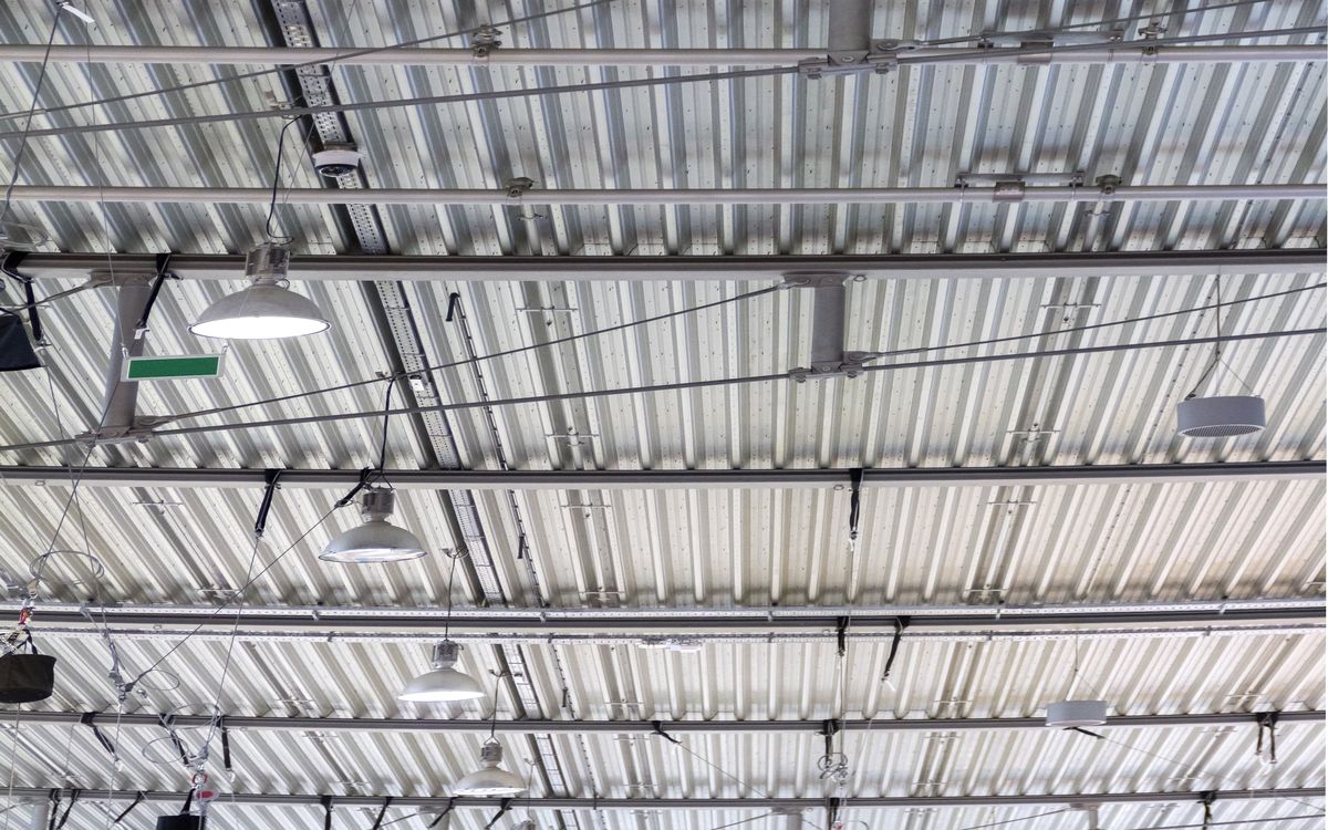 Interior view of a greenhouse with ducting running along the ceiling and heat exchange equipment mounted on a wall